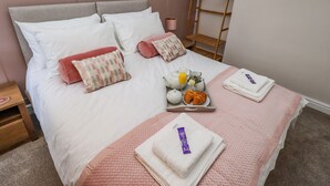 A neatly made bed with pillows, a tray of breakfast items, and folded towels. - Millside (Lincoln)