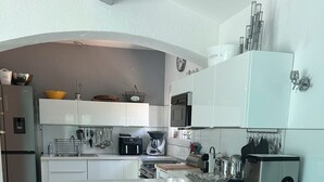 Eine moderne Küche mit einer zentralen Kochinsel, Barhocker, Edelstahlgeräten und einer hängenden Pfannenträgerleiste.