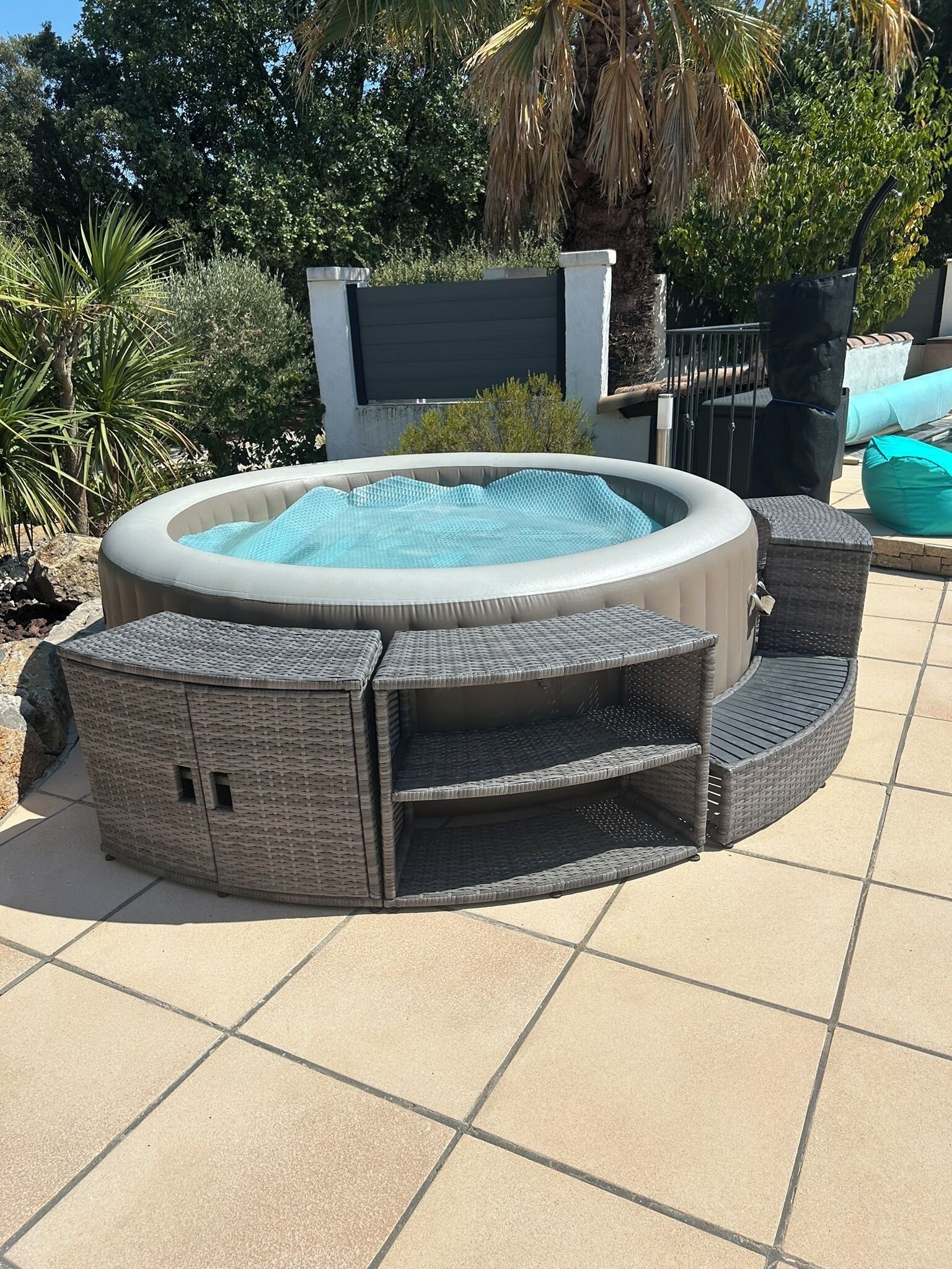 Un bain à remous agrémenté de meubles en osier et d’une terrasse carrelée.