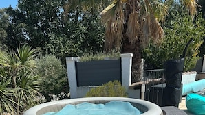 Ein Whirlpool mit Korbmöbeln und einer gefliesten Terrasse.