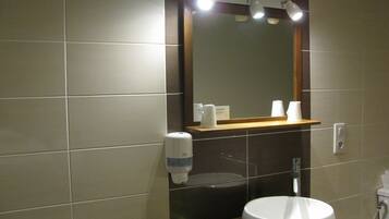 A bathroom with a large mirror, a sink, and a soap dispenser.