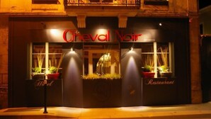 The exterior of the Creval Noir restaurant with illuminated signage and potted plants at the entrance. - Logis Hotel Le Cheval Noir (Argenton-sur-Creuse)