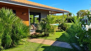 Una casa moderna con patio coperto, piscina e vegetazione lussureggiante.