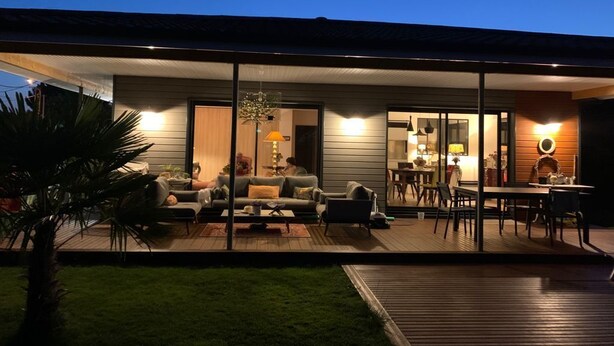 Una casa moderna con un portico coperto, un'area pranzo e una cucina a vista.