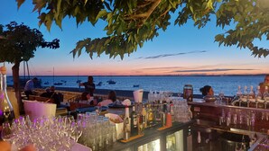 Un ristorante sul mare con posti a sedere all'aperto, un'area bar e vista mare e barche.
