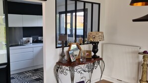 Una cucina moderna con mobili bianchi e un piano di lavoro nero, una zona pranzo con pavimento decorato e un tavolo consolle con oggetti decorativi.