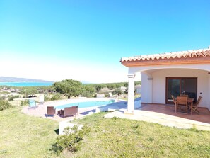 Ein Haus mit Pool, Gartenmöbeln und Meerblick.