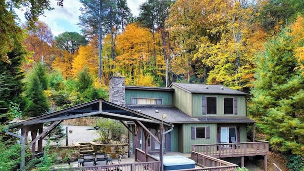 Eine zweigeschossige Hütte mit einer Terrasse, umgeben von Herbstlaub.