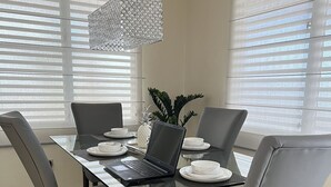 A dining area with a glass table, grey chairs, a laptop, and a pineapple centerpiece. - Beautiful home 10 min from everythin!! (luquillo)