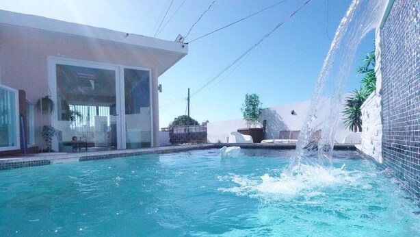 A swimming pool with a water feature, a glass door entrance, and a tiled wall. - Beautiful home 10 min from everythin!! (luquillo)