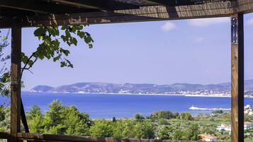 Eine hölzerne Pergola mit Tisch und Stühlen mit Blick auf eine Küstenlandschaft.