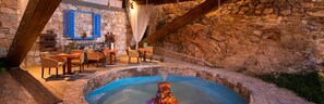 A stone-walled outdoor area with a hot spring, wooden furniture, and a rustic ambiance. - Kallisti Hotel (Thasos)