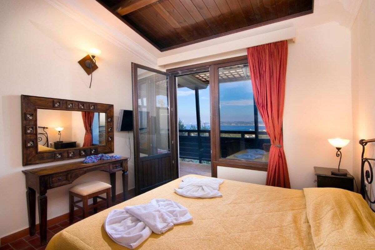 A hotel room with a bed, a desk, a mirror, and a window with curtains.