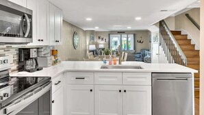 A modern kitchen with white cabinetry, stainless appliances, and a central island. - Coastal Vibes! Walk To Beach & Pool Hilton Head (Hilton Head Island)