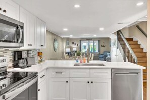 A modern kitchen with white cabinetry, stainless appliances, and a central island.