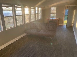 A spacious room with a large window, a sofa, and a desk. - Weekly rental in Pointe Coupee (Jarreau)