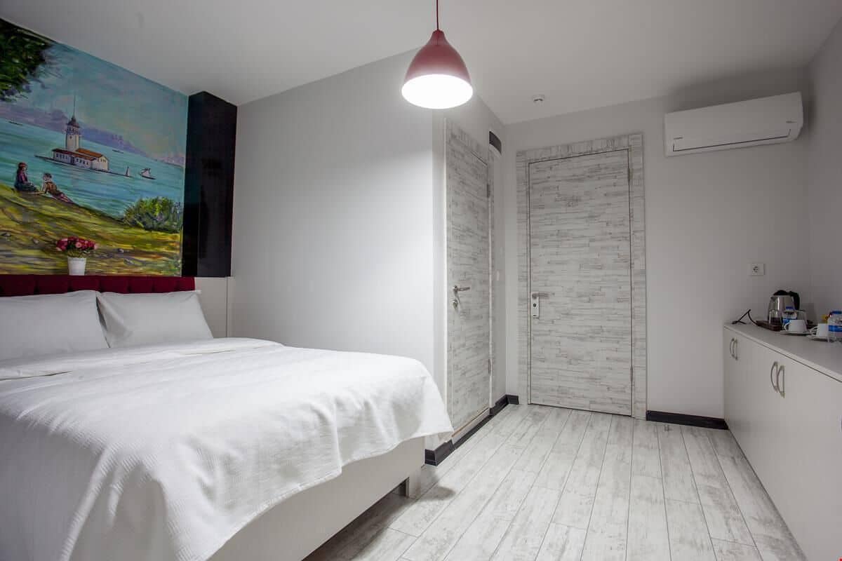 Un dormitorio con cama, un cuadro, un armario y una kitchenette.