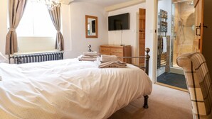 A bedroom with a bed, a dresser, a TV, a shower, and a view of the outdoors. - Christmas Cottage (Alfreton)