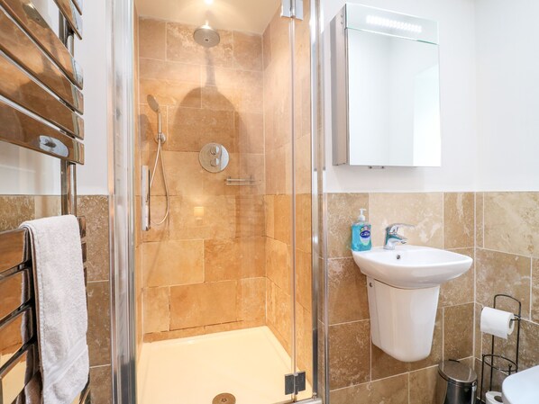Un baño con ducha de vidrio, lavamanos blanco y retrete.