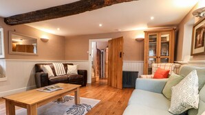 A cozy living room with a wooden coffee table, a sofa, and a bookshelf. - Christmas Cottage (Alfreton)