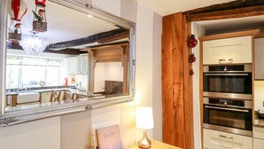 A kitchen with a wooden beam, a large mirror, and a modern oven. - Christmas Cottage (Alfreton)