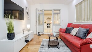 Een moderne woonkamer met een rode bank, een witte entertainmentkast en een grote flatscreen-televisie.
