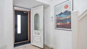Een hal met een zwarte deur, een witte deur met ruitpanelen en een kunstwerk in een lijst aan de muur.