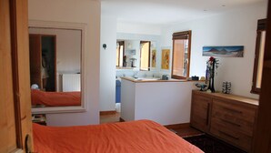A bedroom with a bed, a dresser, a mirror, and a bathroom visible through an open door. - Family house with swimming pool near Nantes (Vertou)