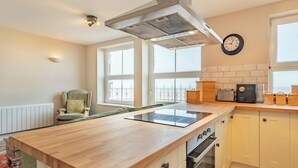 A kitchen with a central island, a stove, oven, and a wall-mounted clock.