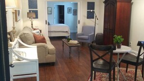 Una sala de estar con un sofá, una mesa de comedor con sillas, una lámpara y un aparador de madera grande.