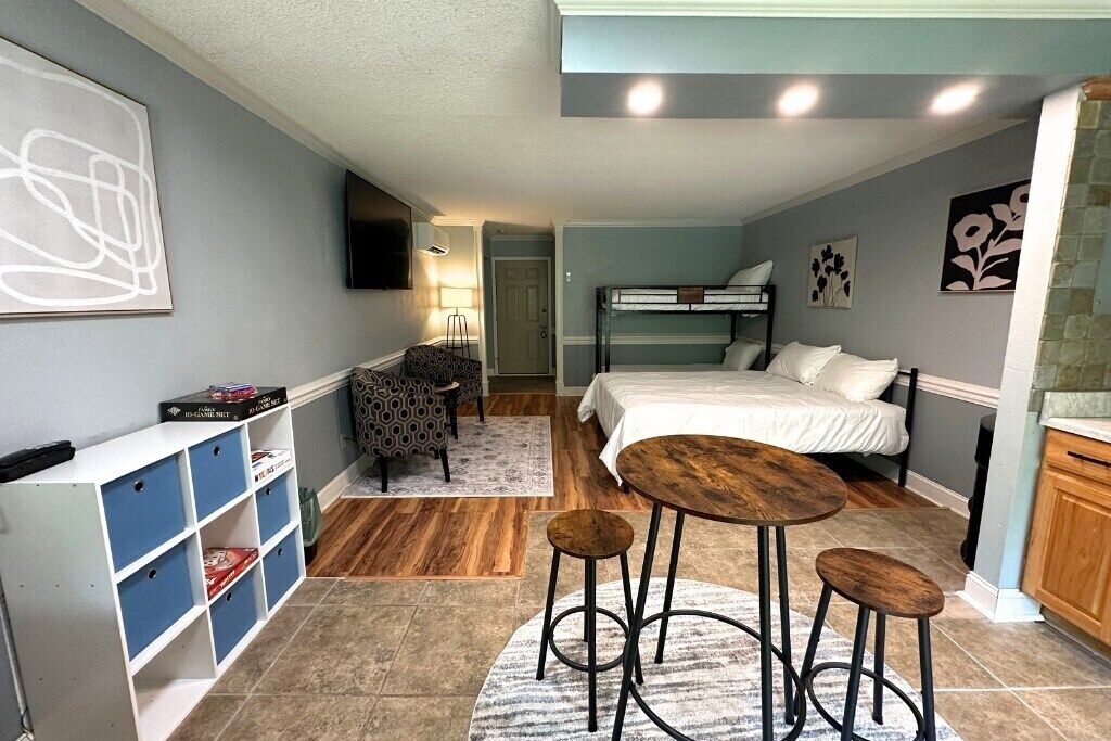 A compact room with bunk beds, a small desk, a chair, and a bar stool.