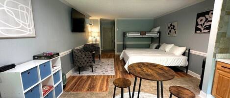 A compact room with bunk beds, a small desk, a chair, and a bar stool.