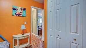 A hallway with orange walls, a white door, and a painting of a cow. - Cozy Riverfront Cabin (Mendota)
