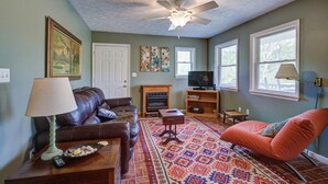A living room with a leather sofa, a patterned rug, a television, and a fireplace. - Cozy Riverfront Cabin (Mendota)