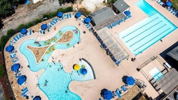 An aerial view of a swimming pool area with a wave pool, lounge chairs, and a separate pool.