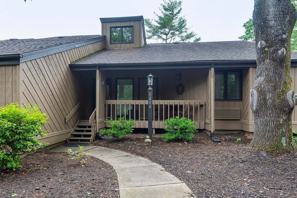 A two-story building with a covered porch, a small staircase, and a pathway leading to the entrance.