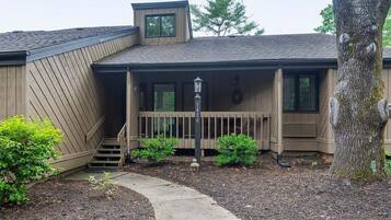 A two-story building with a covered porch, a small staircase, and a pathway leading to the entrance.