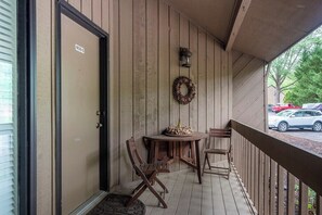 A porch with a door labeled '408-C,' a small table with chairs, a lantern, and a wreath. - Fairway VIlla 1406 at Rumbling Bald (Lake Lure)