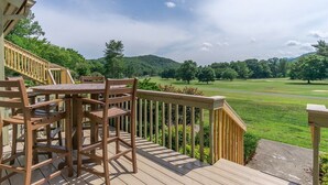 A wooden deck with a table and chairs, overlooking a golf course. - Fairway Villa 502 at Rumbling Bald (Lake Lure)