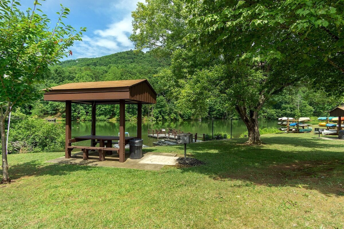 Un kiosque en bois avec des bancs, une poubelle et un quai avec des bateaux.