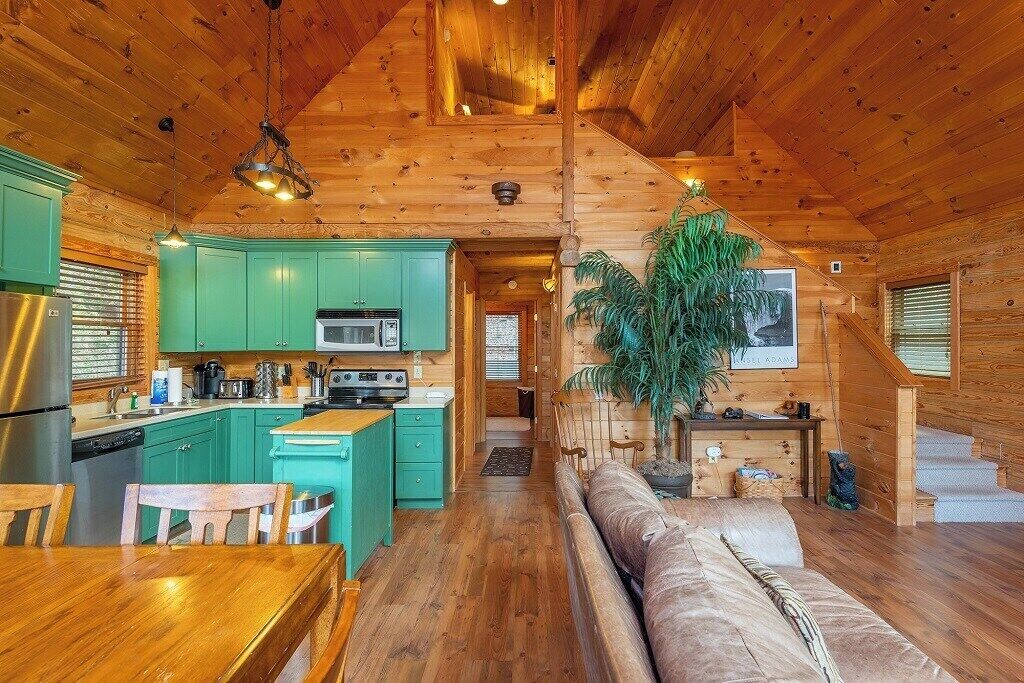 L’intérieur d’un chalet en bois comprend une cuisine, un coin repas et un salon avec un canapé.