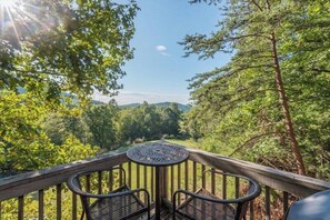 Une terrasse avec une table ronde et deux chaises, donnant sur une zone boisée.