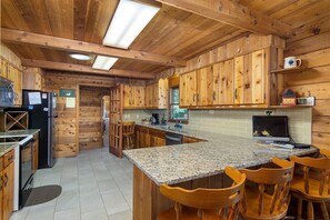 A kitchen with wooden cabinets, granite countertops, and a central island with bar stools.