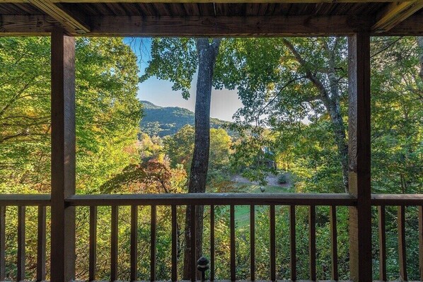 A wooden deck with a view of a forested area and hills.