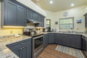 A kitchen with dark cabinets, stainless steel appliances, and a granite countertop.