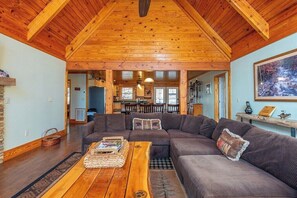 A cozy living room with a wooden ceiling, a sectional sofa, and a coffee table.
