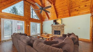 A spacious living room with a large sectional sofa, a fireplace, and a ceiling fan.