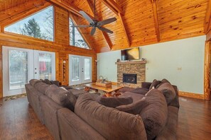 A spacious living room with a large sectional sofa, a fireplace, and a ceiling fan.