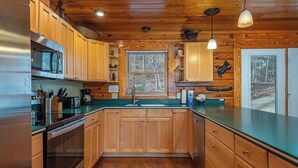Une cuisine avec des meubles en bois, des appareils en acier inoxydable et un plan de travail vert.