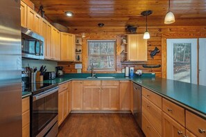 A kitchen with wooden cabinets, stainless steel appliances, and a green countertop.